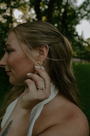 Close-up detail of delicate jewelry and tattoo art against a white halter dress.
