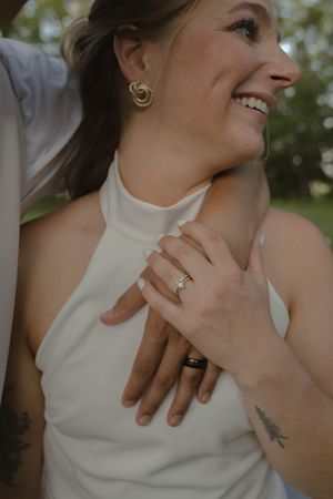 Elegant wedding jewelry and ring details shown against a white halter neckline.