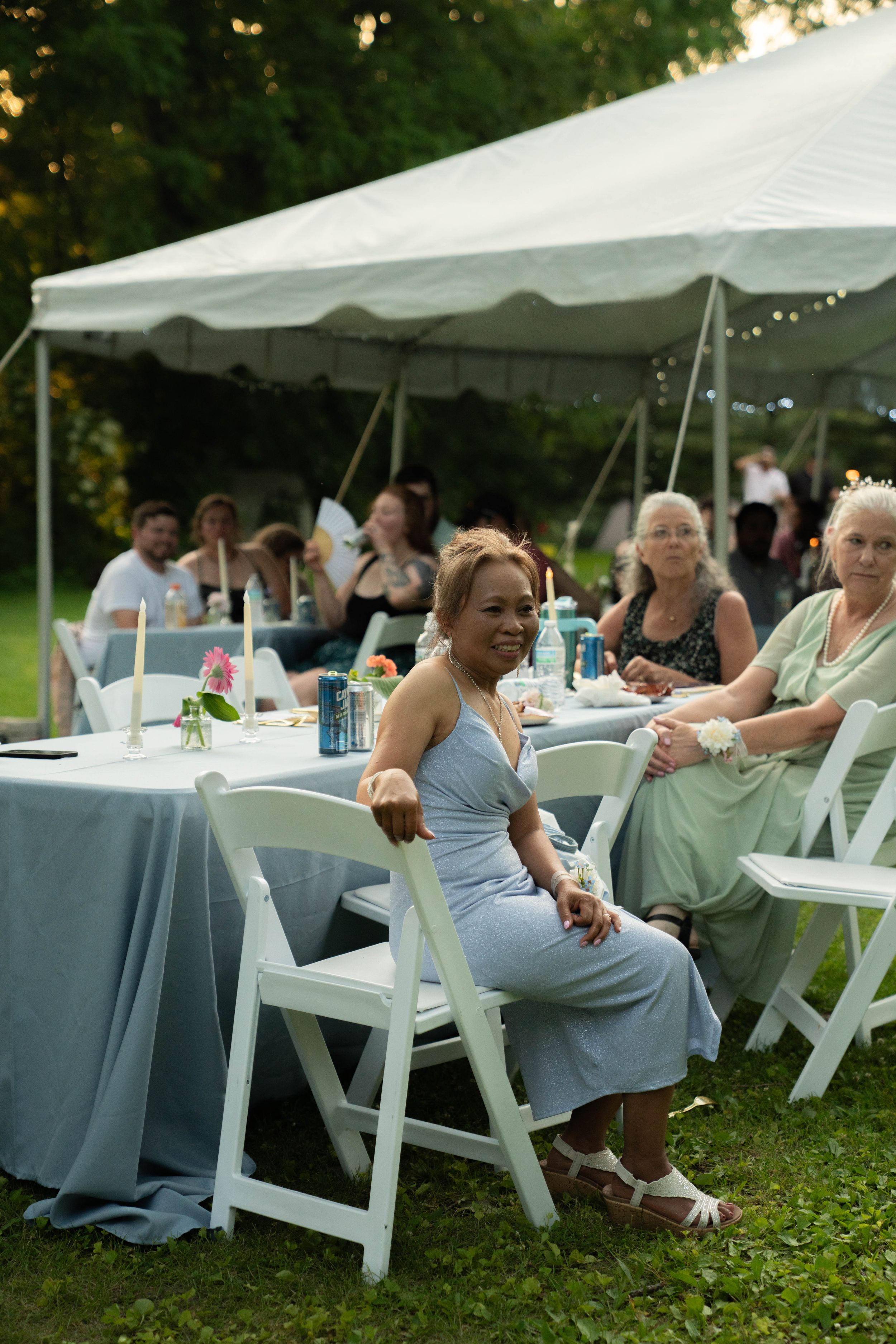Outdoor wedding reception setup with white tents and tables on a grassy lawn.