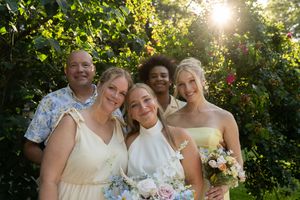 Joyful wedding party poses together in golden evening light with colorful bouquets.