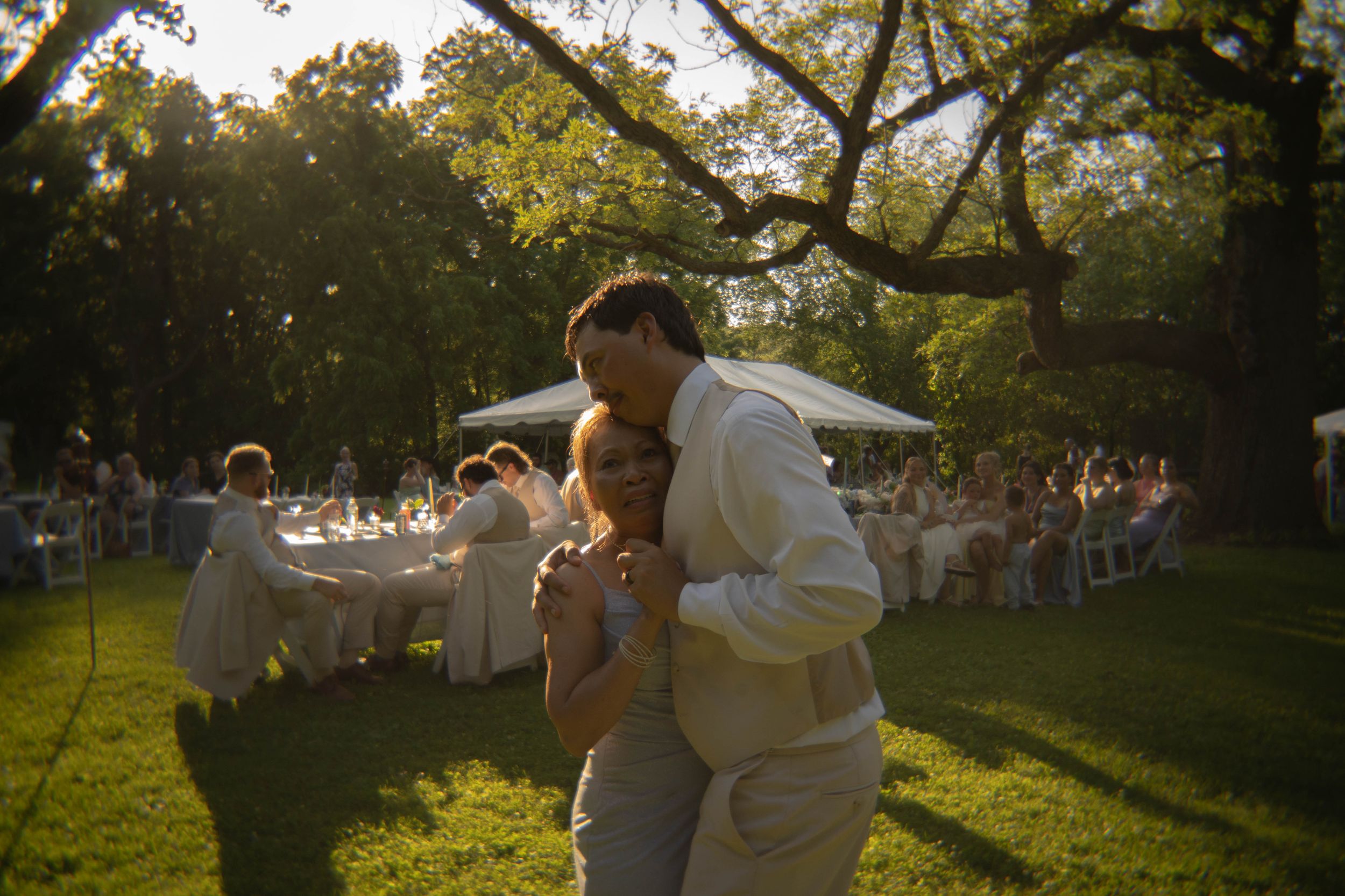 Wedding guests dancing outdoors at sunset under golden light.
