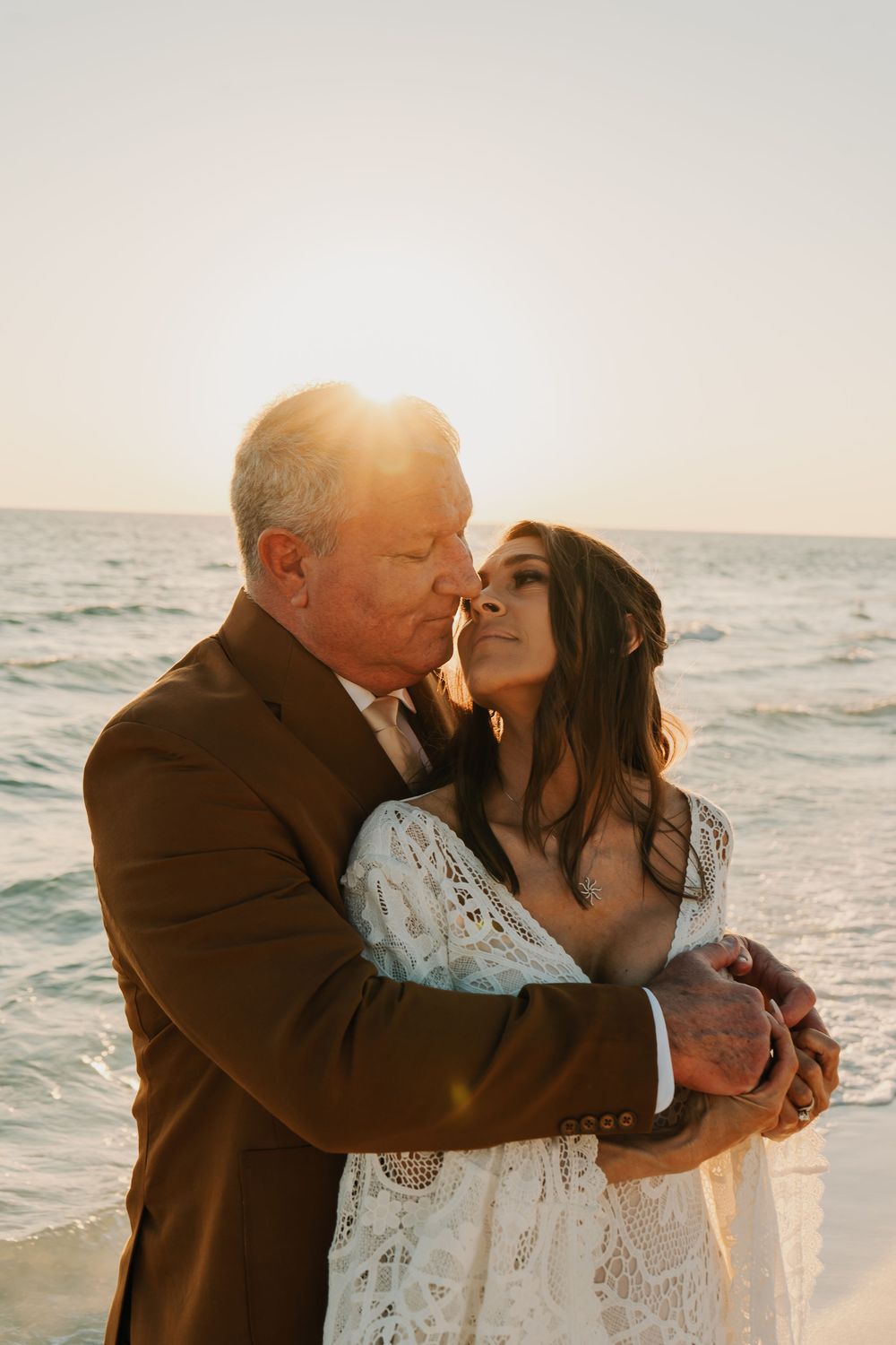 A couple shares an intimate moment on the beach during golden hour sunset.