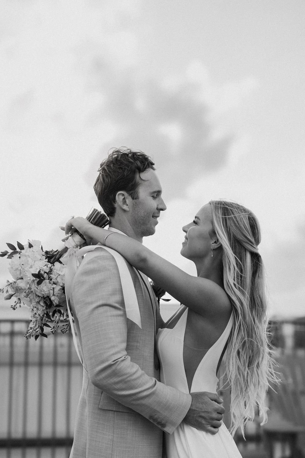 A romantic wedding couple embraces and laughs together in black and white photographs.