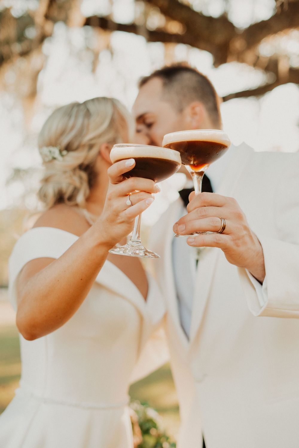 Wedding guests raise champagne glasses in an elegant toast at an outdoor celebration.