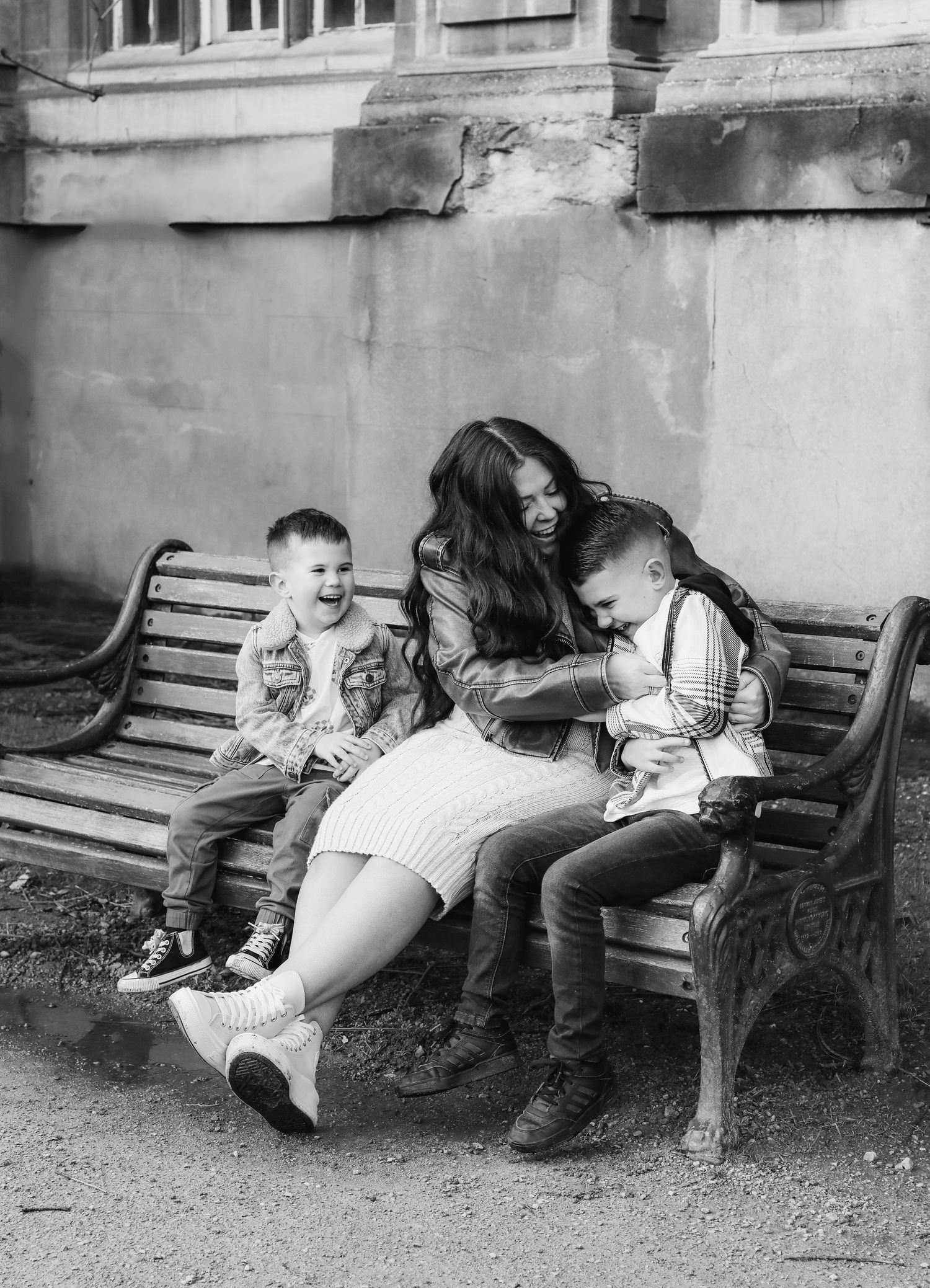Black and white photo showing family playfully laughing on a bench during family shoot in Nottingham