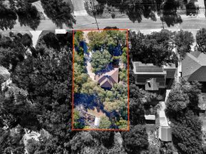 Overhead aerial view of a rectangular residential lot outlined in red surrounded by dense tree canopy in Texas.