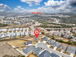 Aerial view of a new residential subdivision near The Rim shopping center in San Antonio, Texas, with rolling hills.