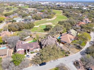 Aerial view of luxury homes bordering a golf course with a city skyline visible in the background in Texas.