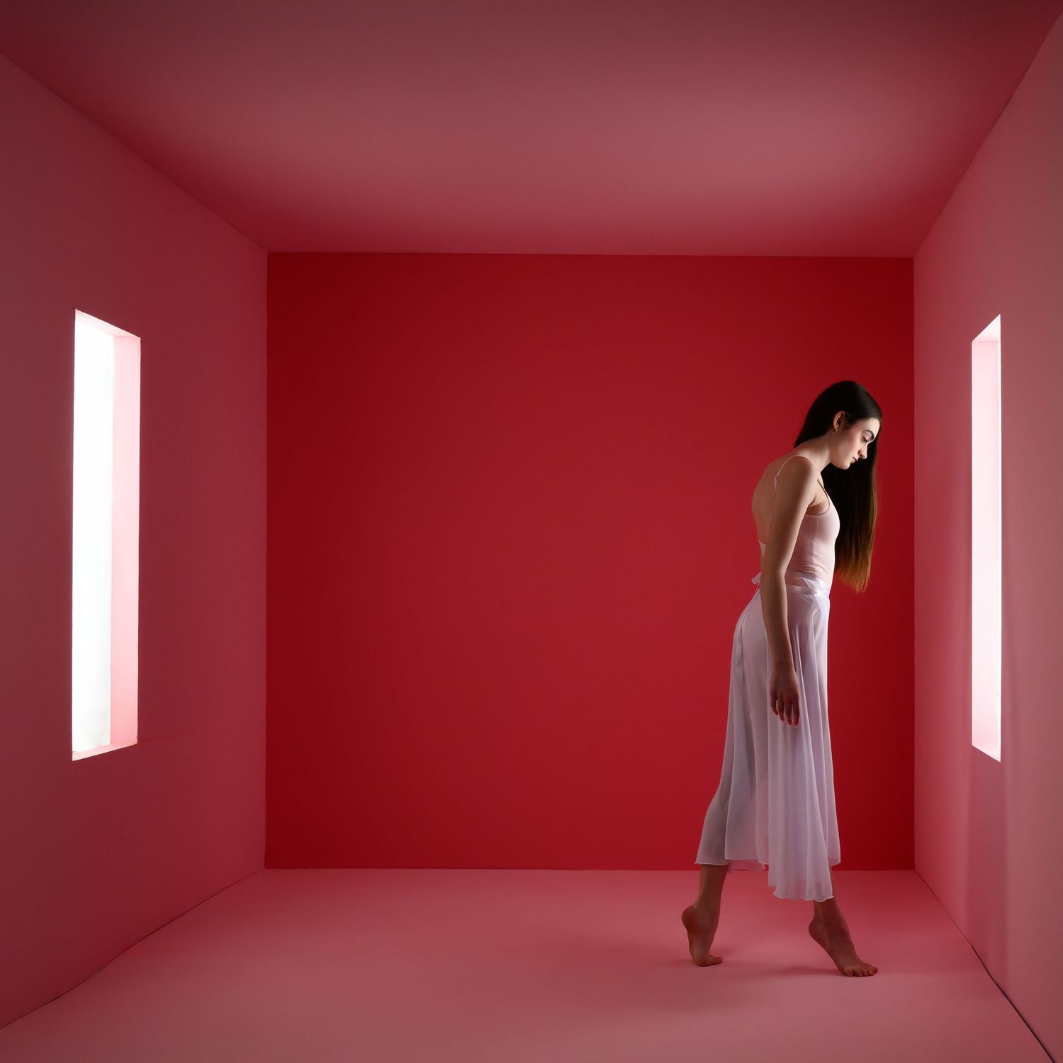 Interpretive dance sequence in minimalist red room with natural window lighting.