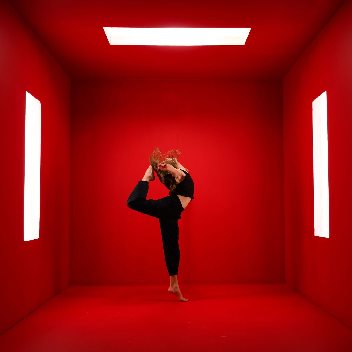 Modern dance movements captured in vibrant red studio space.