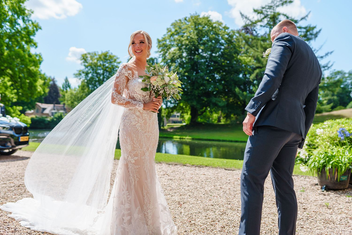 A wedding couple poses together in an elegant conservatory with peach and cream floral bouquets.