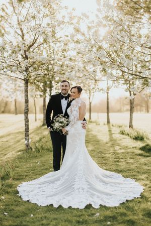Wedding couple embraces under dreamy spring orchard with white blossoms at Laceby Manor - image captured by Grimsby photographers.