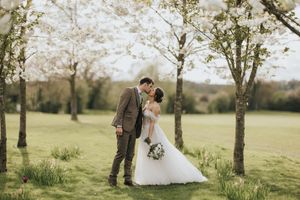 A romantic wedding couple share a tender moment under blooming spring trees at Laceby Manor - image captured by Grimsby photographers.