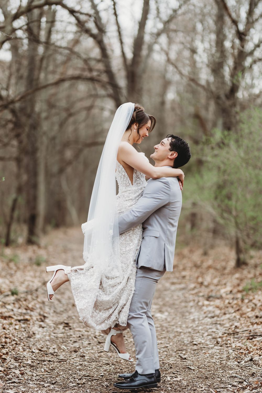 In a rustic autumn forest setting, a couple shares an intimate moment during their wedding photoshoot as the bride dips backwards.