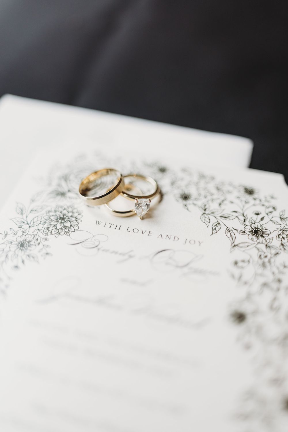 Two elegant wedding rings rest on a white textured surface with delicate floral designs in a romantic composition.