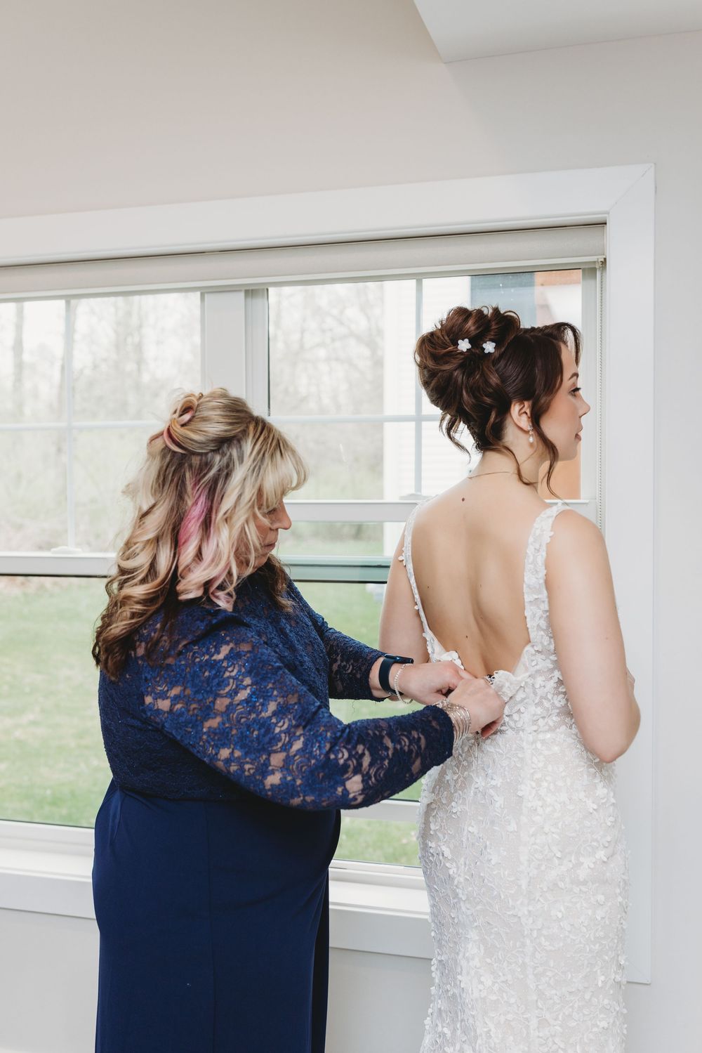 A series of photos showing someone helping with a white wedding dress zipper, in a bright room with windows.