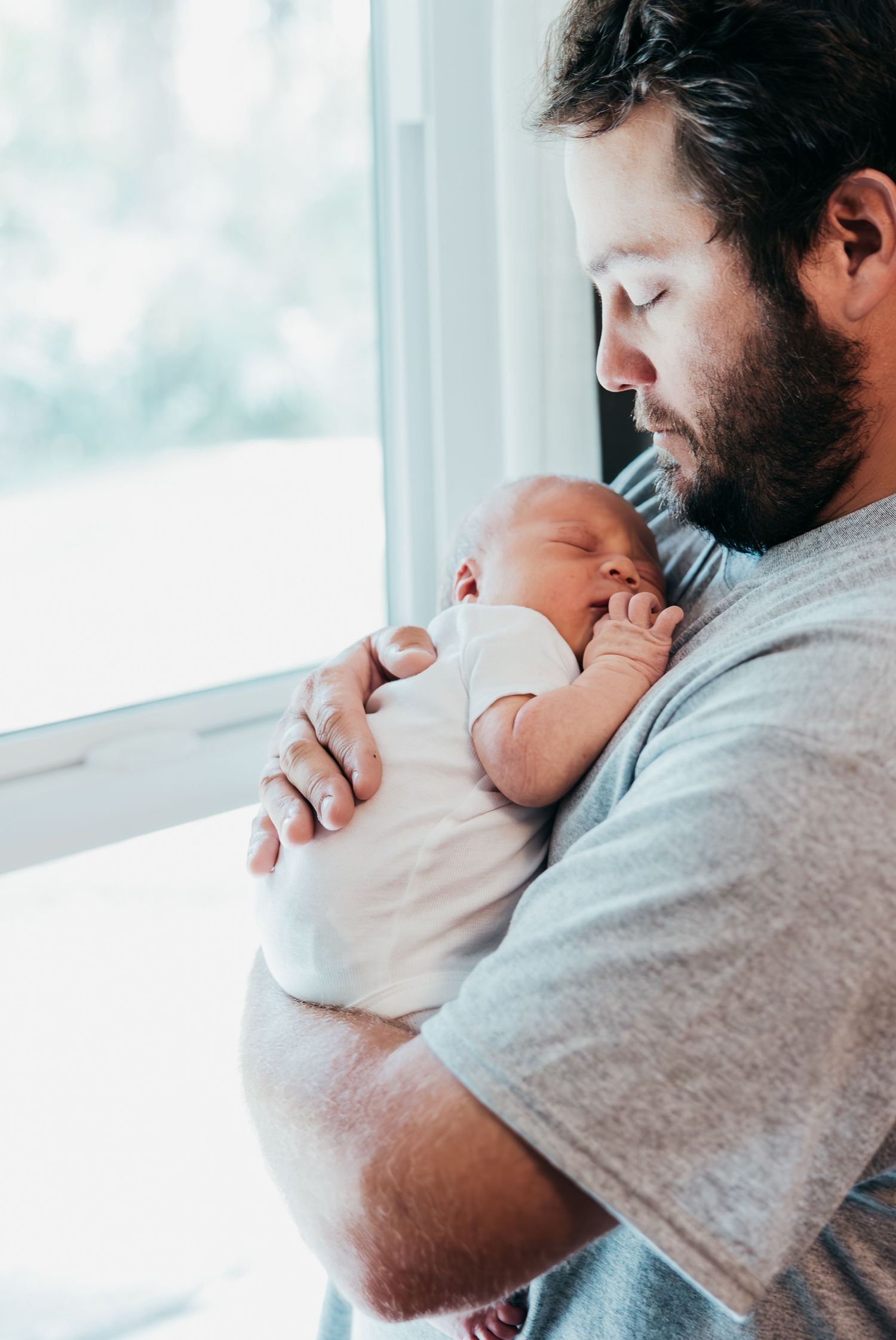 New family cuddling their newborn during in-home lifestyle session in Stuart Florida, newborn photographer in home session, treasure coast