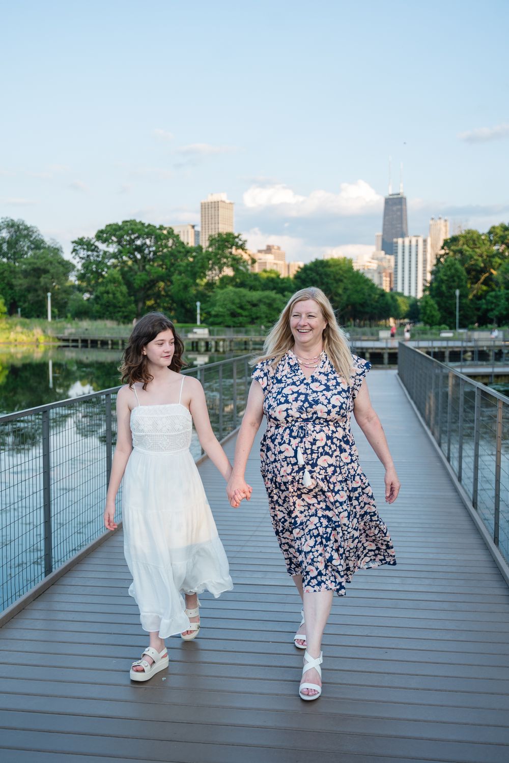 Family walking together on a wooden boardwalk with city skyline and trees in the background.