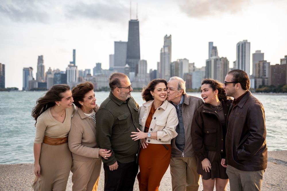 A family laughing and embracing together along Chicago's lakefront with city skyline in background at sunset.