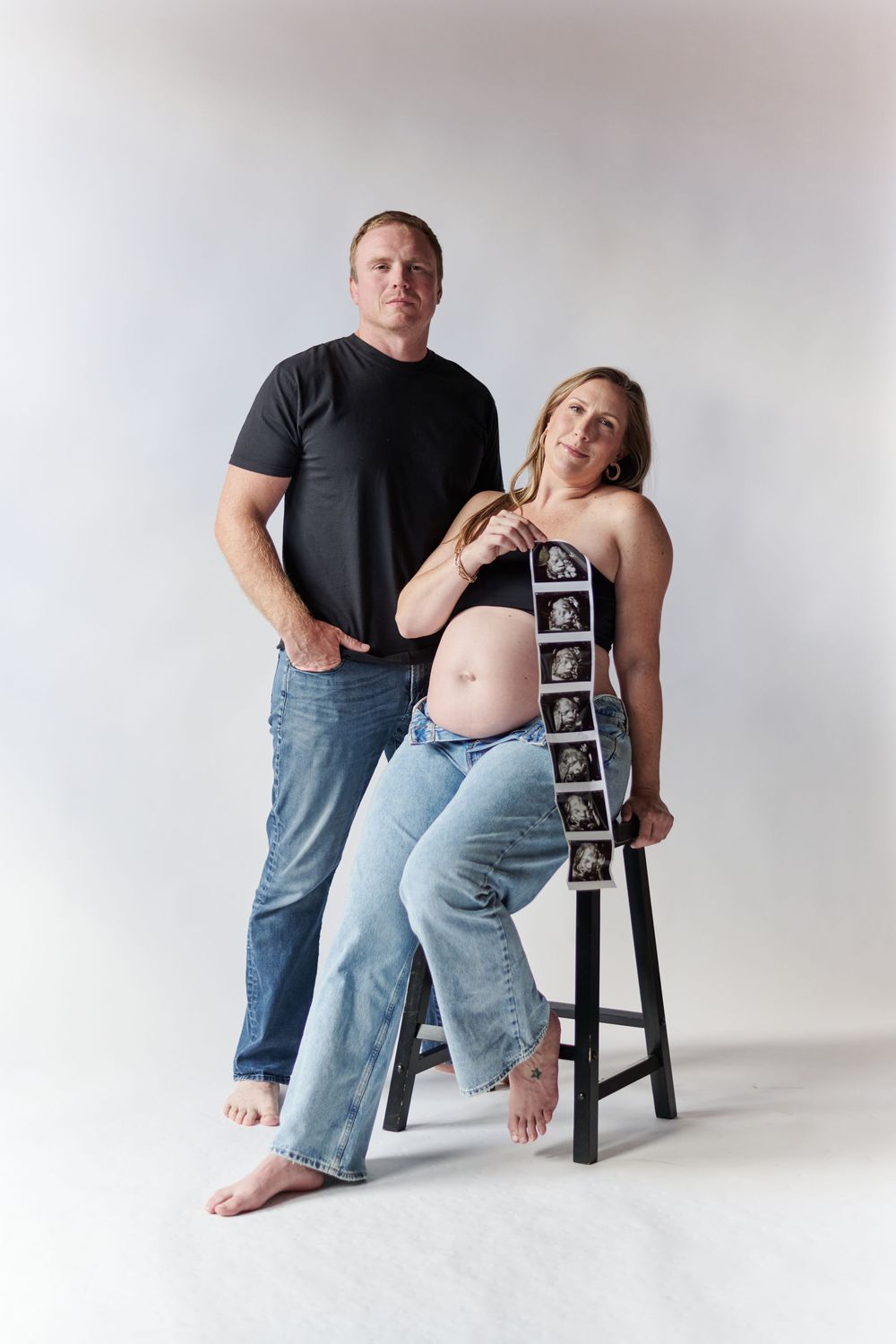 A maternity photo series shows an expectant couple posing with ultrasound photos while sitting on a stool against white backdrop.