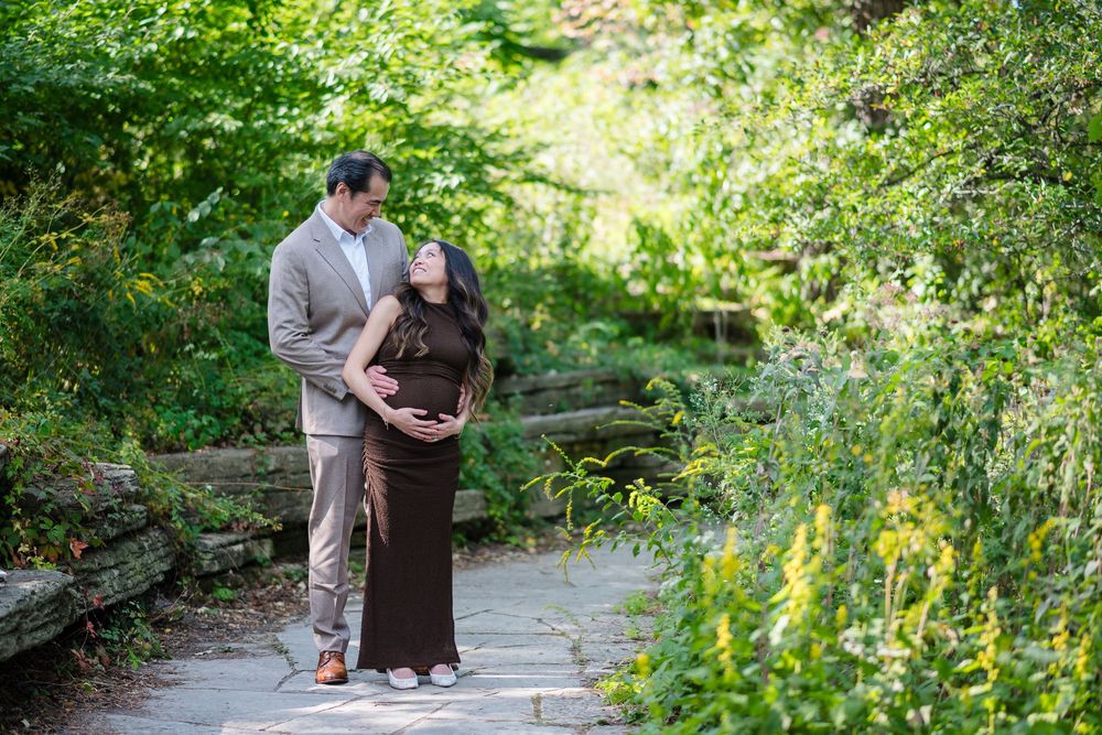 A couple shares a romantic moment together on a garden path surrounded by lush greenery and natural light.