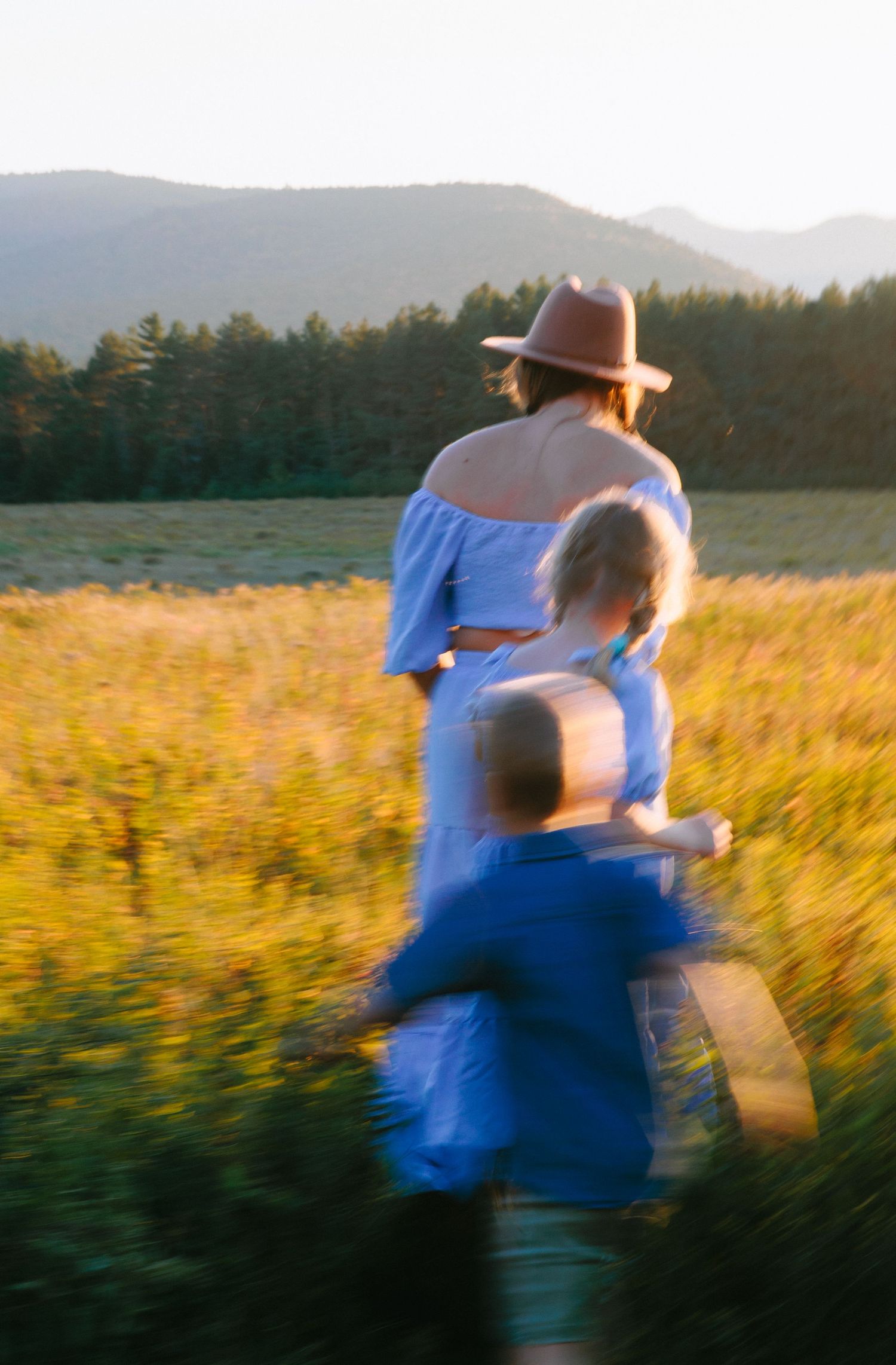 Motion-blurred sequence of a couple dancing and twirling in a sunlit meadow during golden hour.
