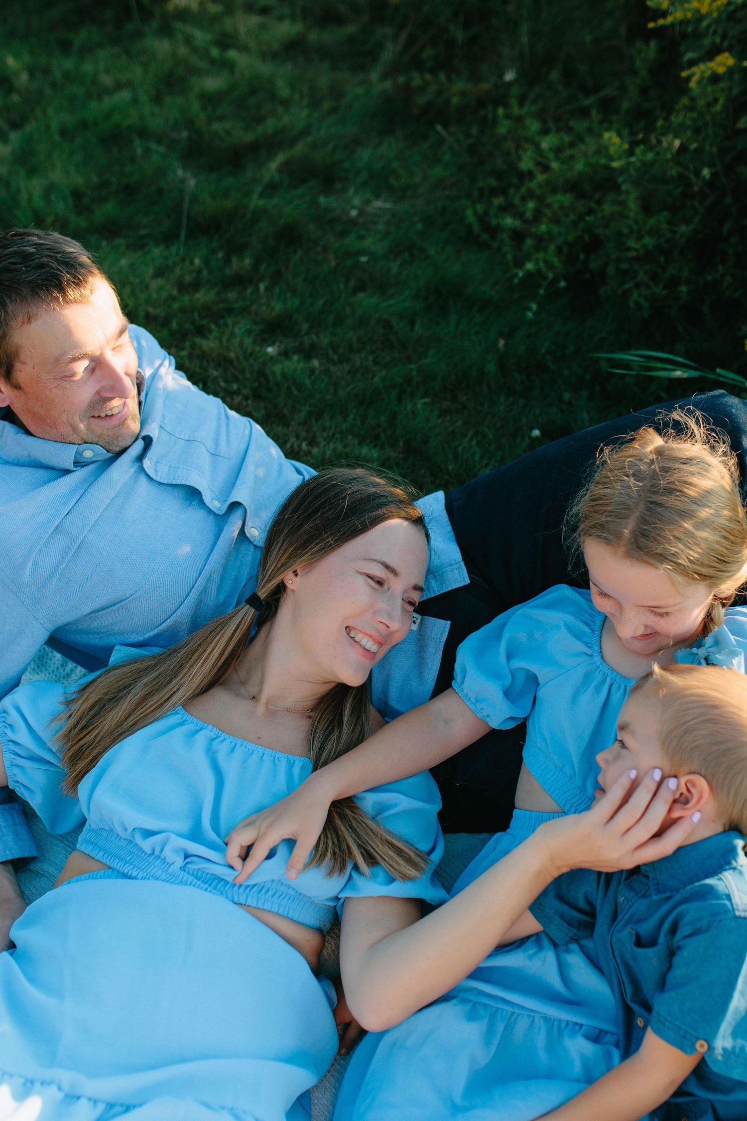 A couple in light blue clothing shares tender moments together while lying down outdoors in a series of connected photos.