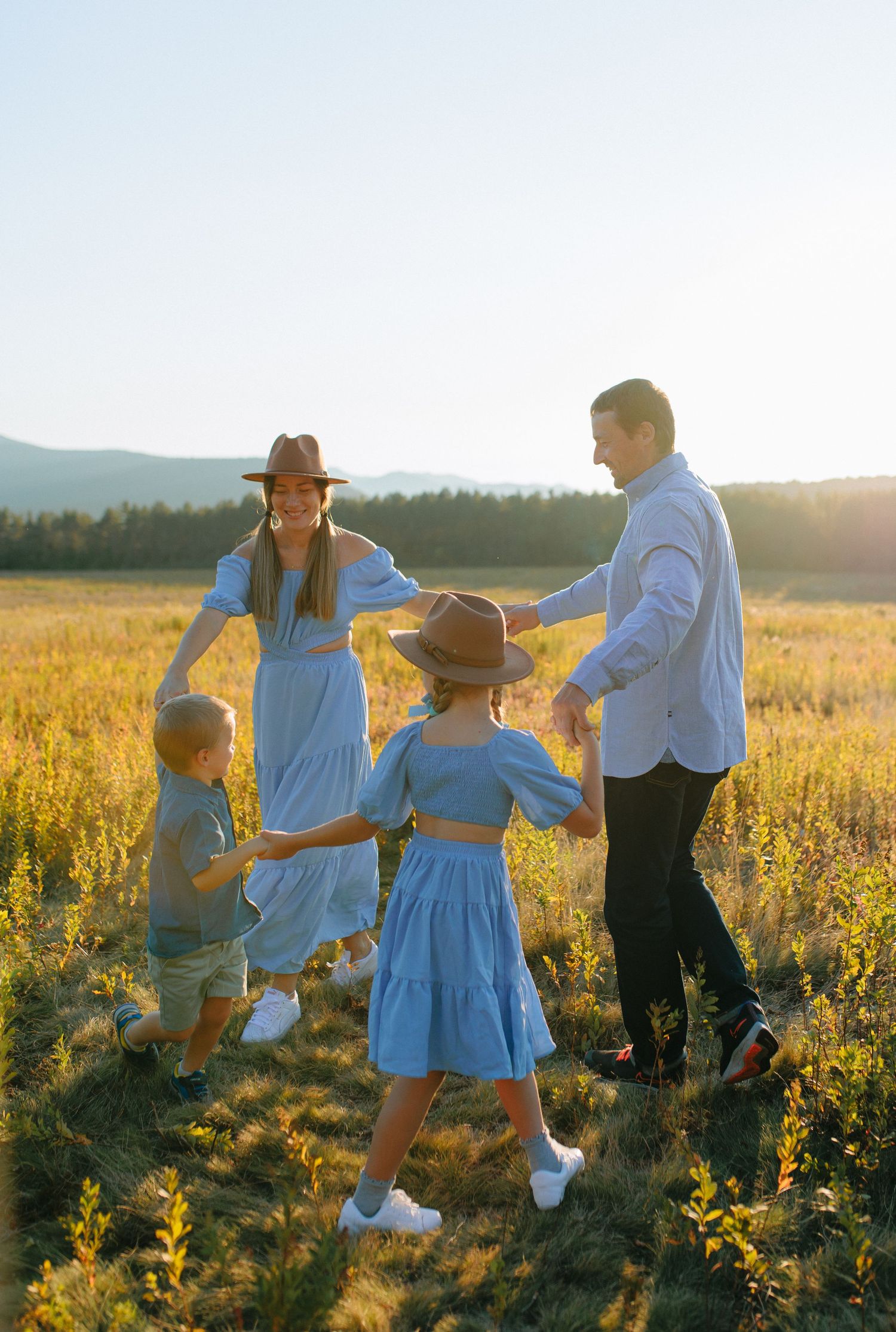 A family enjoys a tender moment together in a sunlit meadow filled with wildflowers during golden hour.