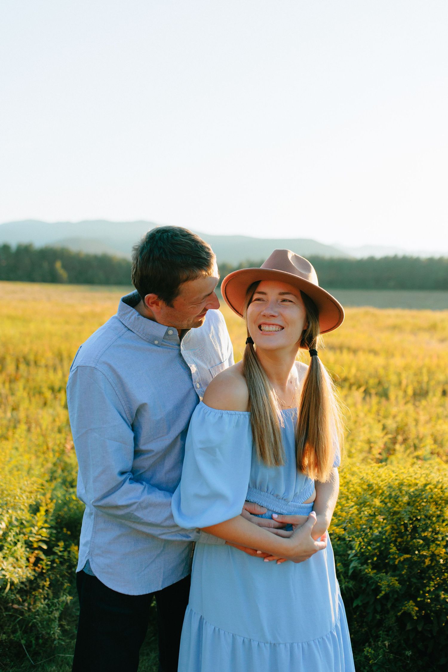 A couple shares tender moments together in a golden field of wildflowers at sunset.