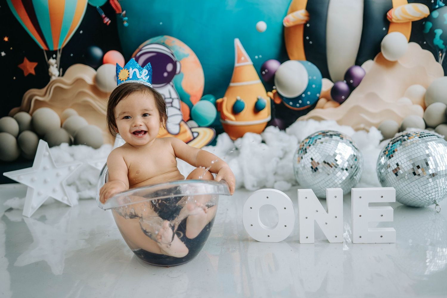 Collage of first birthday cake smash photos with turquoise and white decorations and balloons.