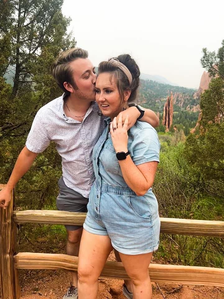 Couple sharing romantic moments on a wooden deck overlooking scenic red rock mountains in the background.