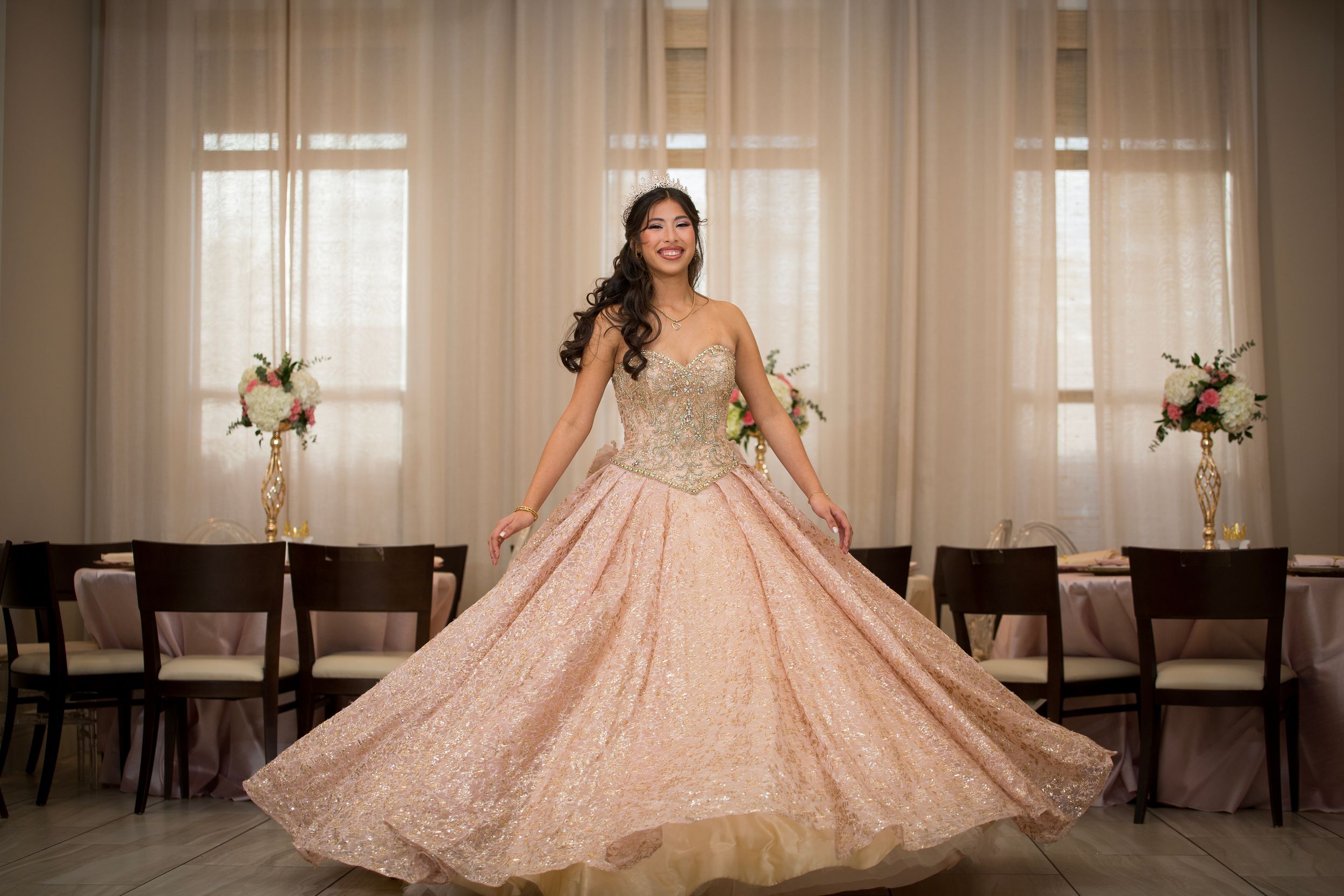A stunning rose gold quinceañera ball gown with intricate beading sparkles in an elegant reception venue.