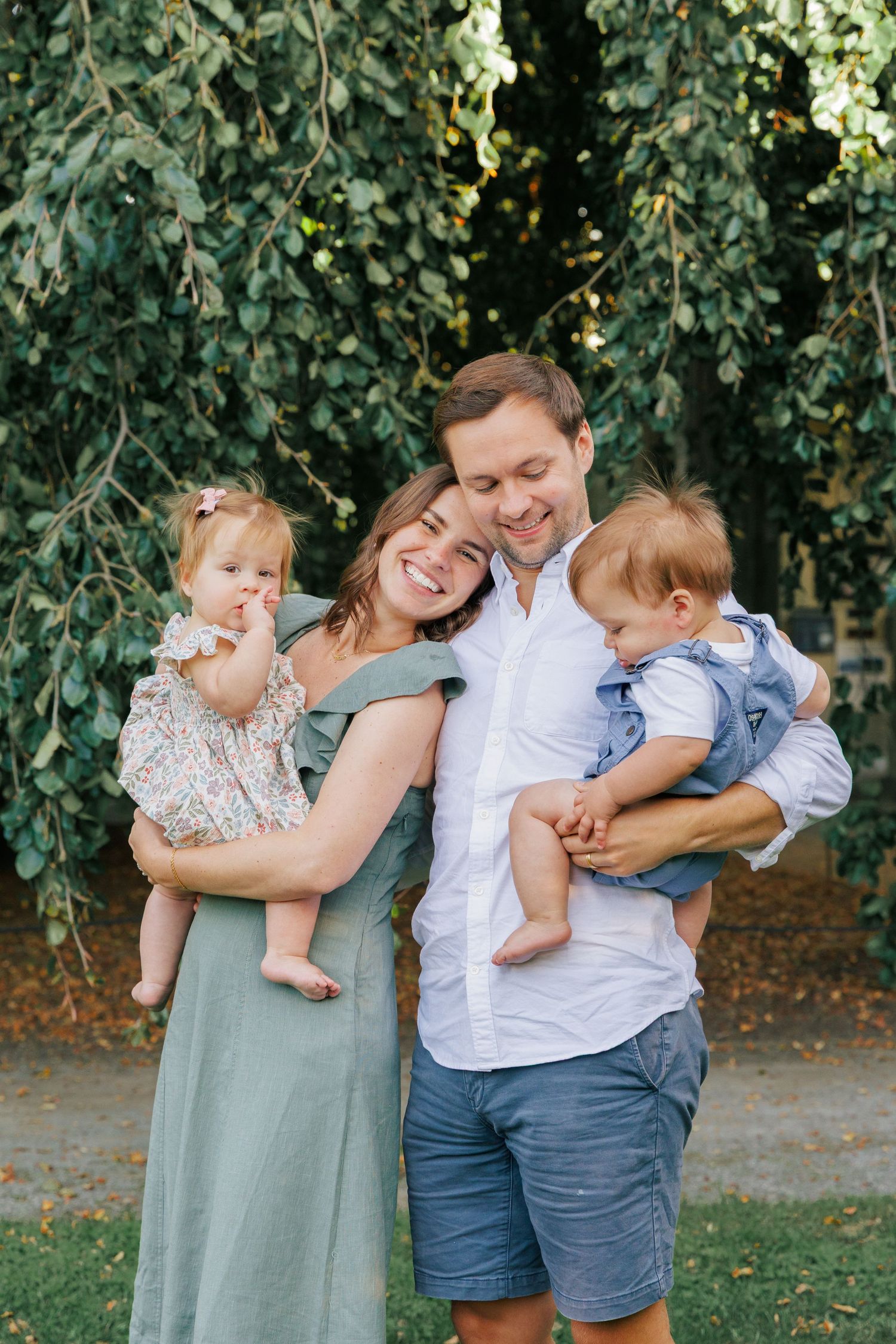 A candid family portrait series taken against lush green garden scenery.