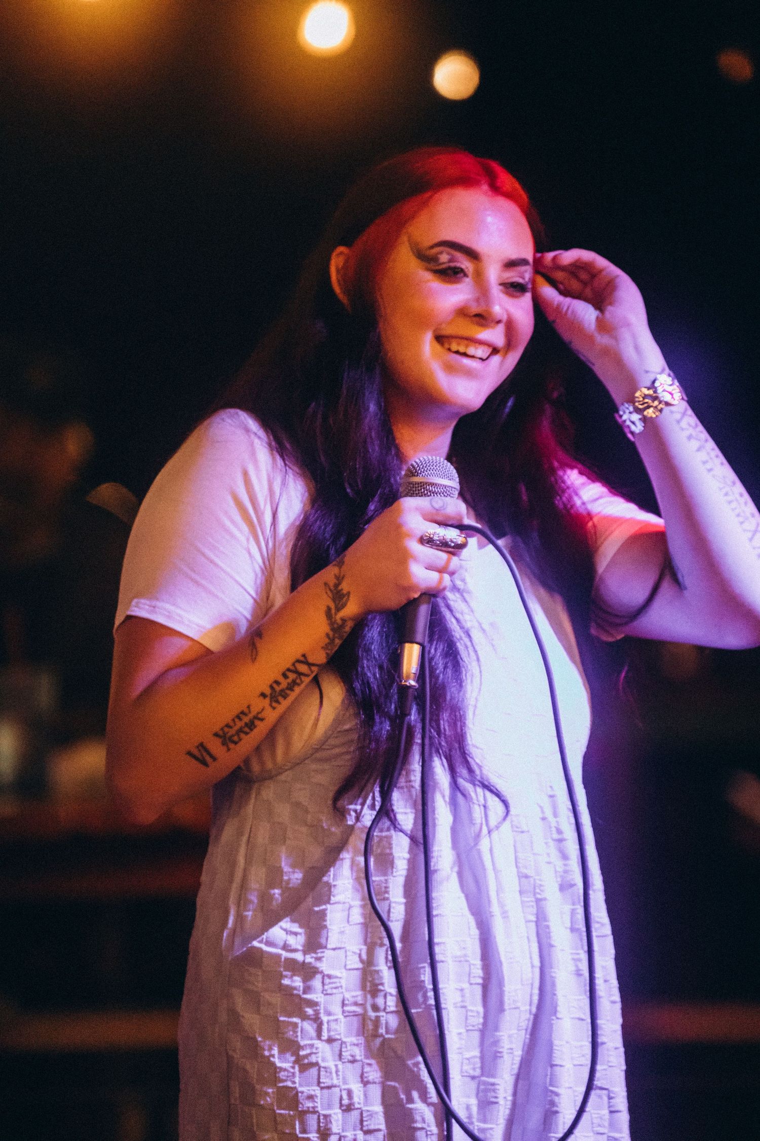 Black and white photo of someone in a white dress performing on a dark stage with star lights in the background.