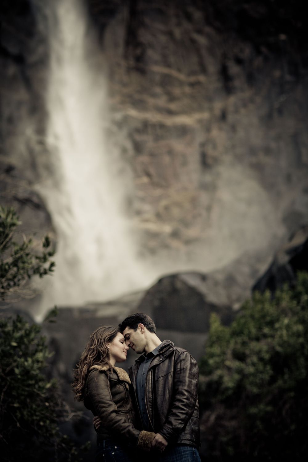 A romantic moment captured in front of a majestic waterfall.