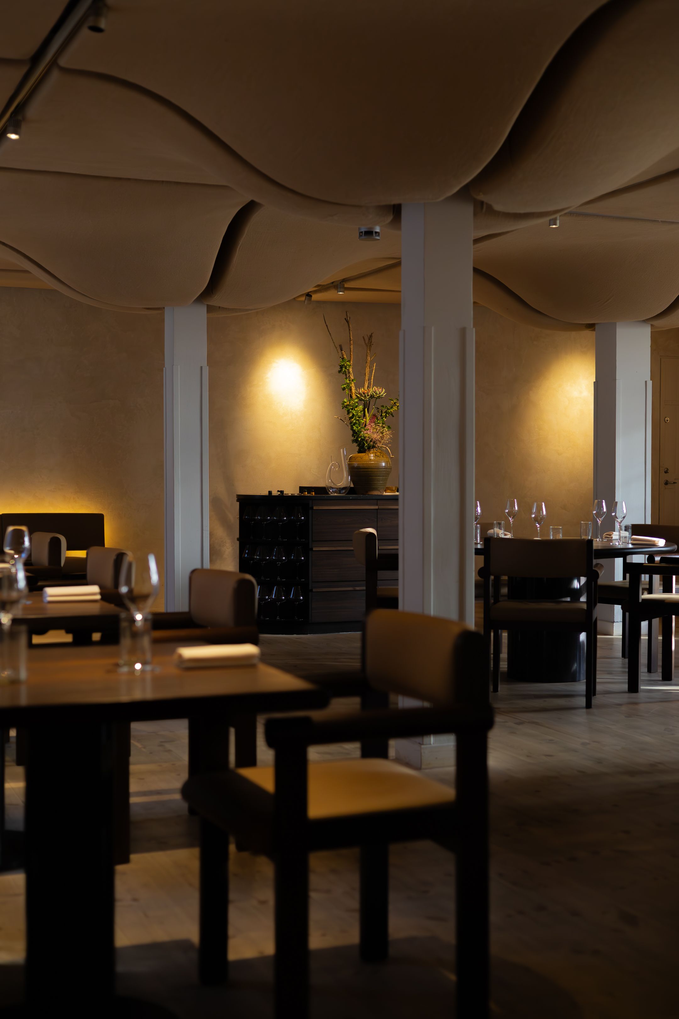 Dimly lit modern restaurant interior with minimalist black tables and warm accent lighting.