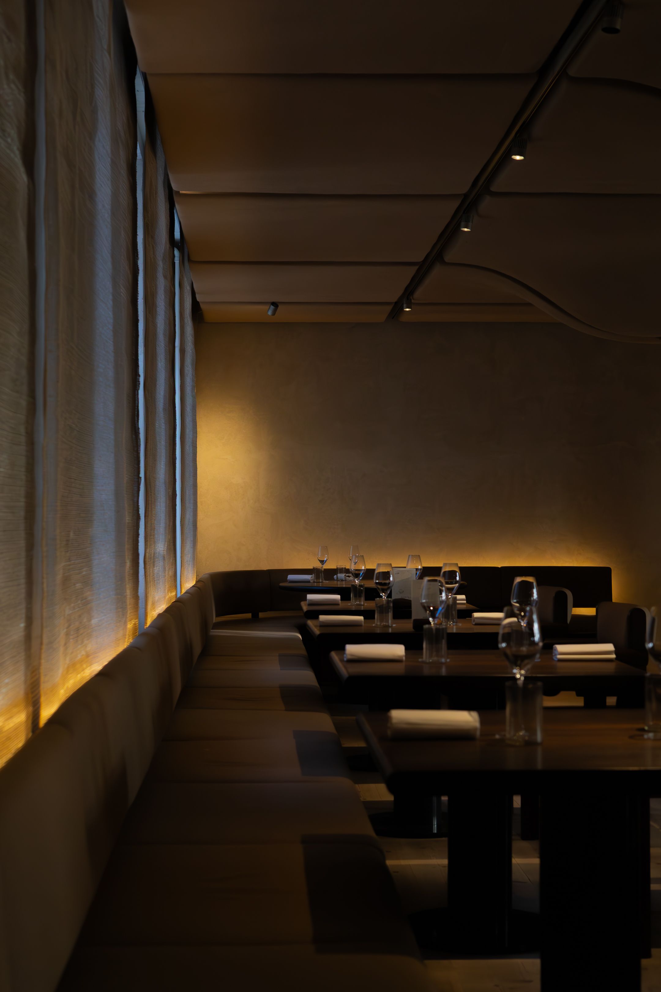 Contemporary dining space with dark wooden tables arranged in a moody atmospheric setting.