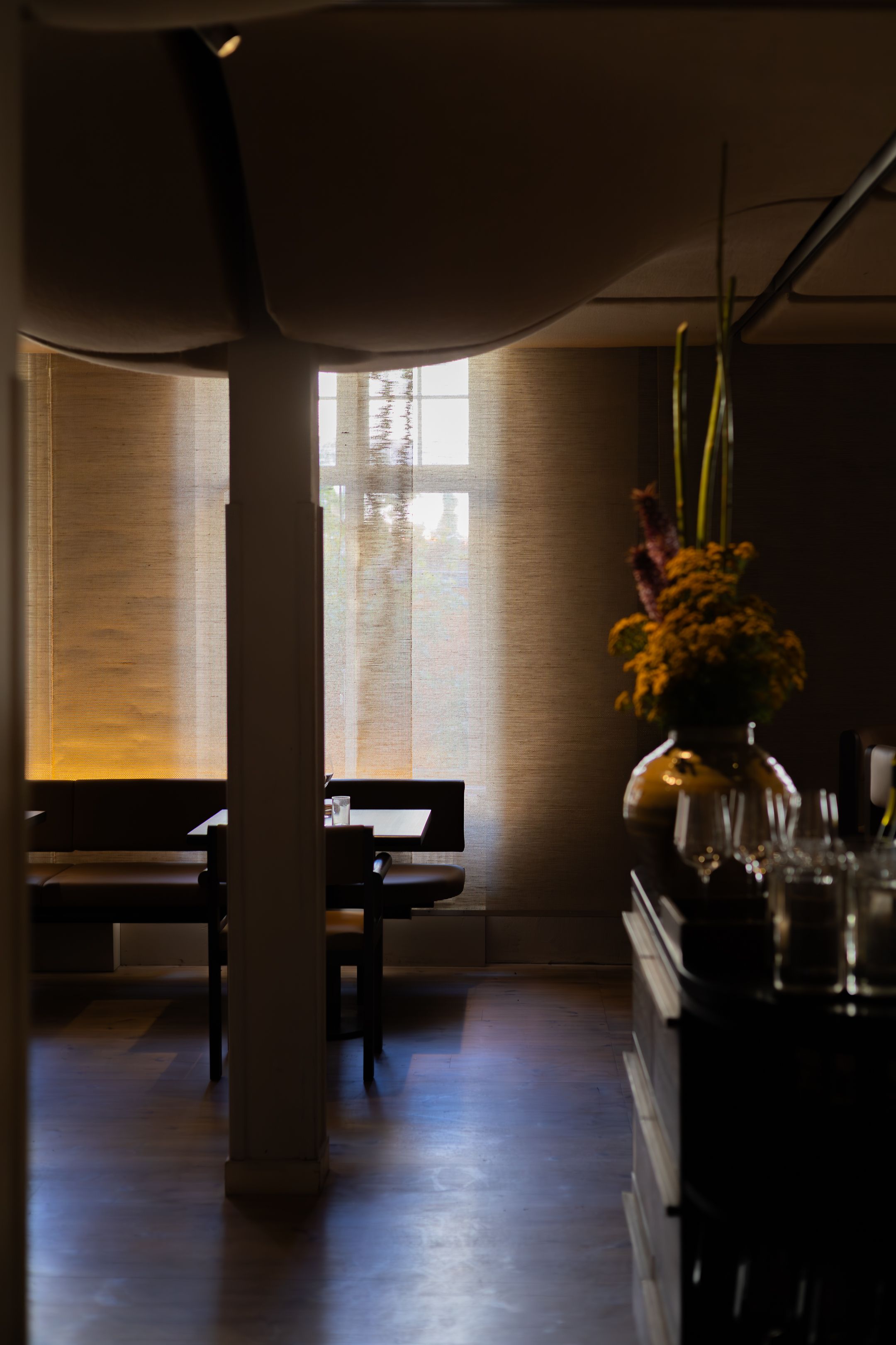Elegant restaurant interior with soft lighting and floral arrangement by the window.