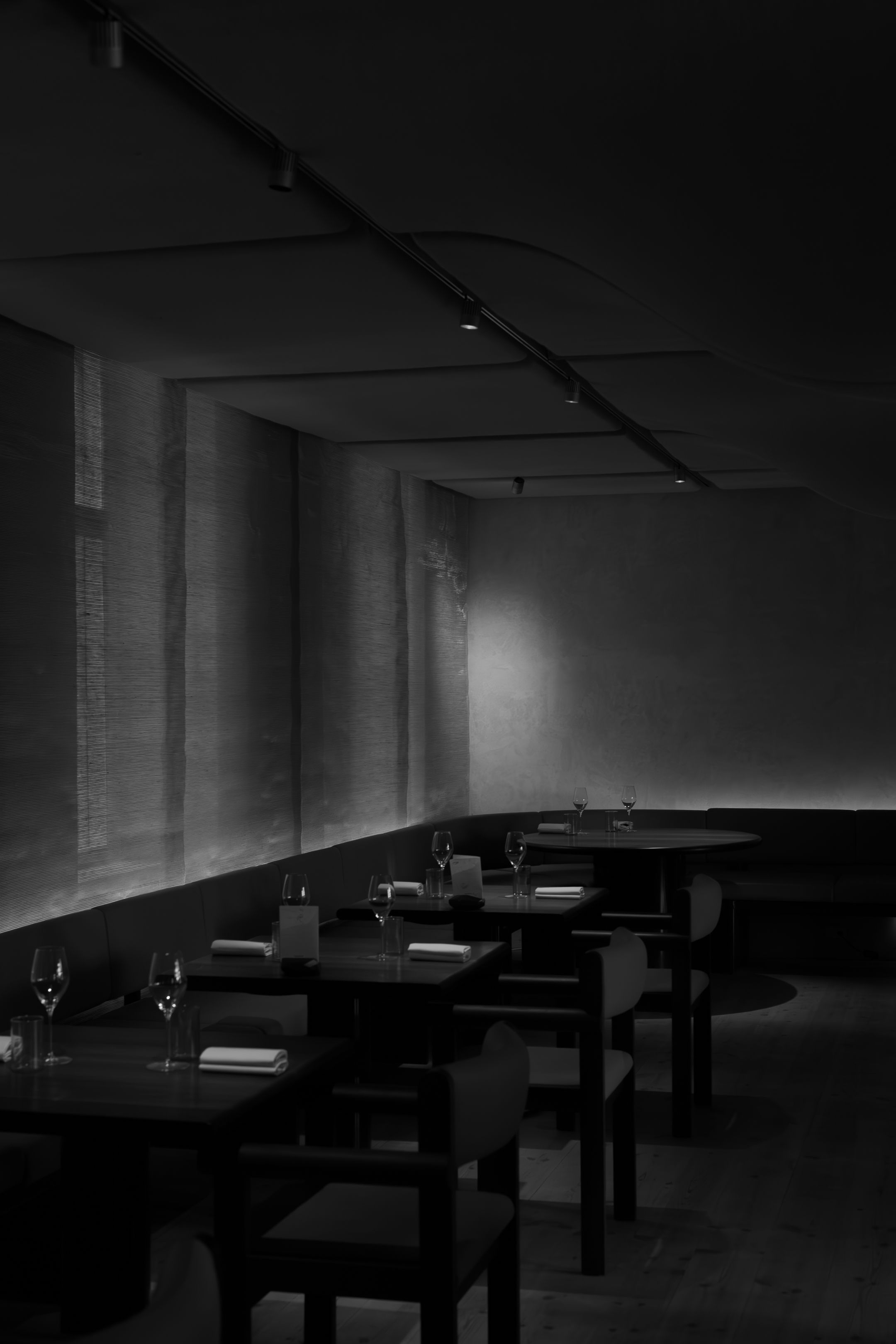 Minimalist restaurant dining room in black and white with empty tables and chairs.