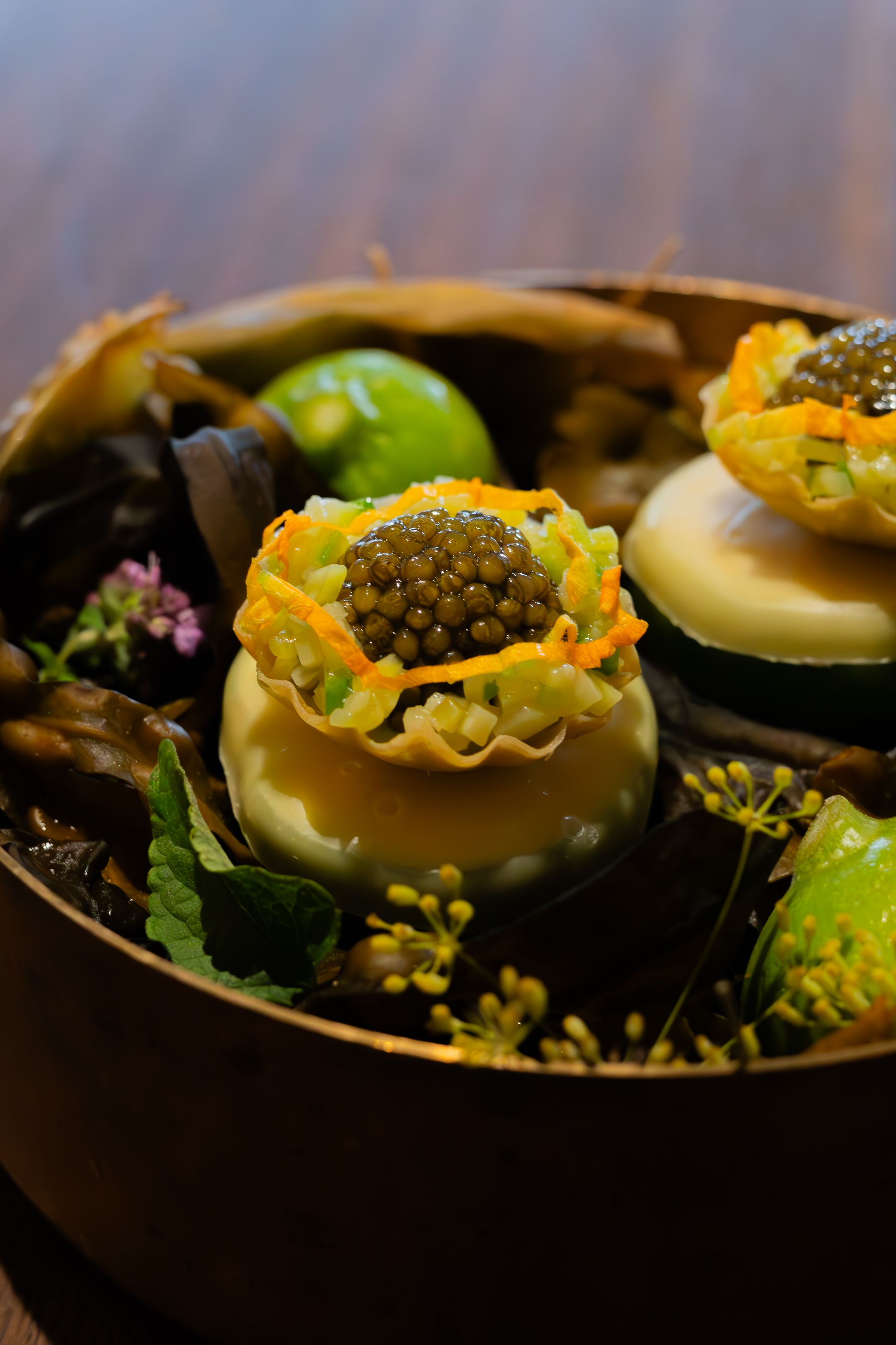 Gourmet appetizers served with caviar garnish on dark plates.