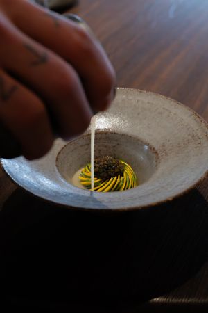 Close-up sequence showing a golden yellow yolk being gently stirred in a rustic bowl on a dark wooden surface.