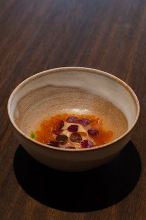 Small ceramic bowls containing dessert with cranberries arranged in a sequence on a dark wooden surface.