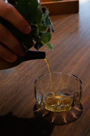 Golden liquid being poured into crystal glasses on a wooden table.