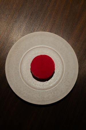 White ceramic plate with a bold red circular design in the center shown in progressive stages.