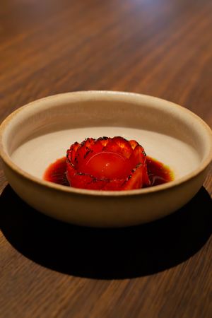 Red berries or fruit arranged artistically in white ceramic plates on a wooden surface.