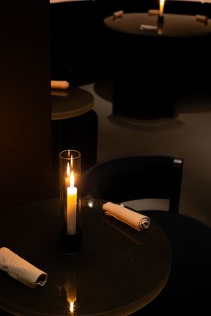 Candlelit table setting with rolled napkins creating an intimate dining atmosphere.