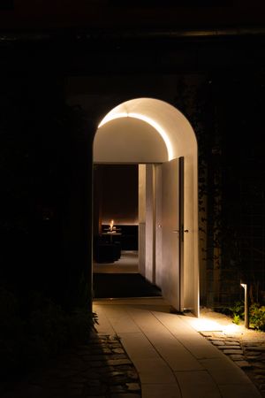 Illuminated arched walkway with benches creating a dramatic nighttime architectural perspective.