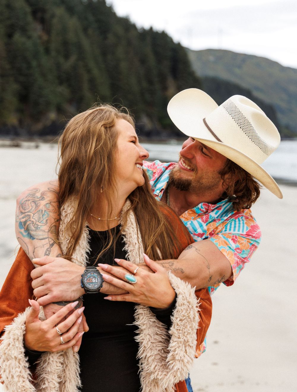 A romantic series of candid kisses and embraces on a beach with mountains in the background.