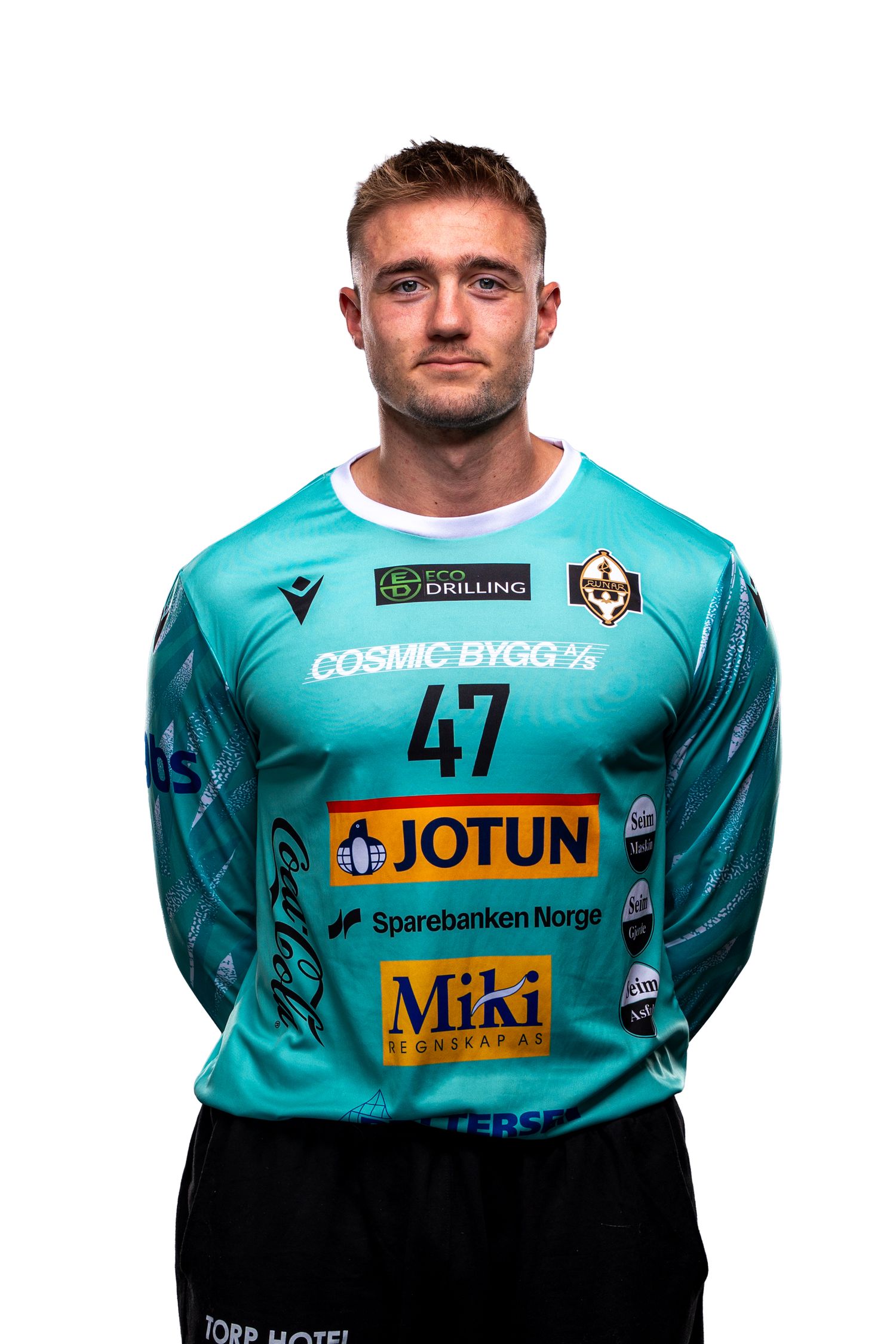 Soccer player wearing a turquoise jersey with Jotun and Miki sponsorship logos against white background.
