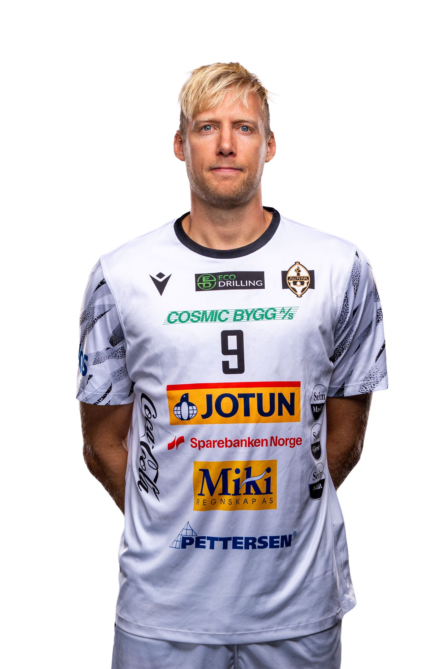 Soccer player wearing white jersey with multiple sponsor logos including Jotun, Miki and Cosmic Bygg.
